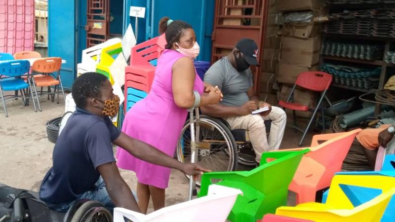 African man in wheelchair taking notes with two other people with impairments next to him