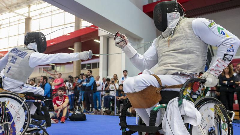 Two wheelchair fencers competing on a piste