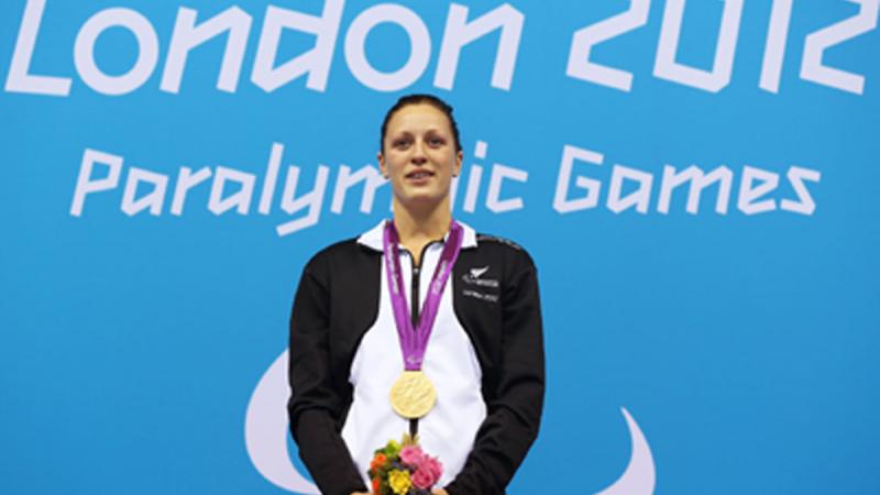 A picture of a woman with a gold medal around her neck during a medal ceremony