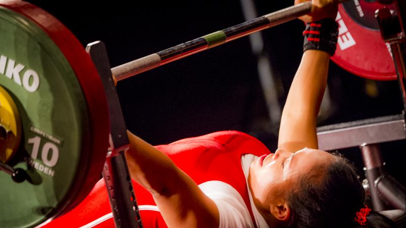 A woman preparing to lift a bar on a bench press 
