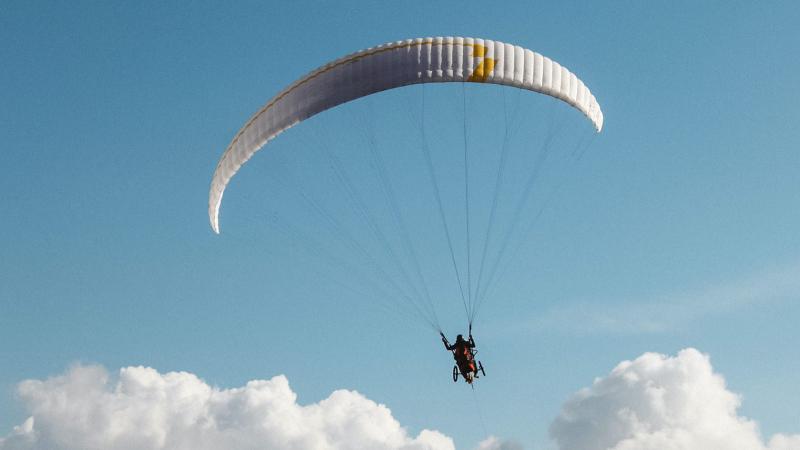 Person in wheelchair attached to another guide as on a parachute