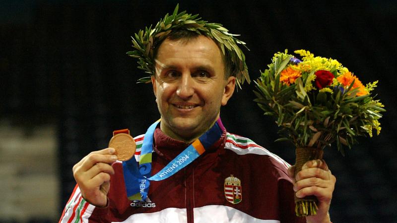 Man smiling with medal and flowers