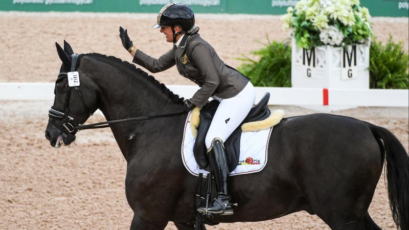 Woman riding horse and patting it on the head