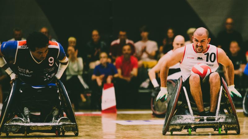 Man in wheelchair tries to move the ball while opponent tries to defend him