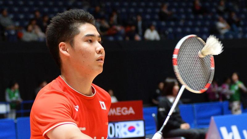Japanese male badminton player in wheelchair hits a return