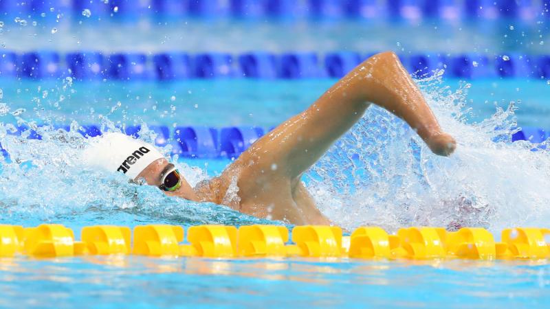 A male swimmer without his left hand swimming a pool
