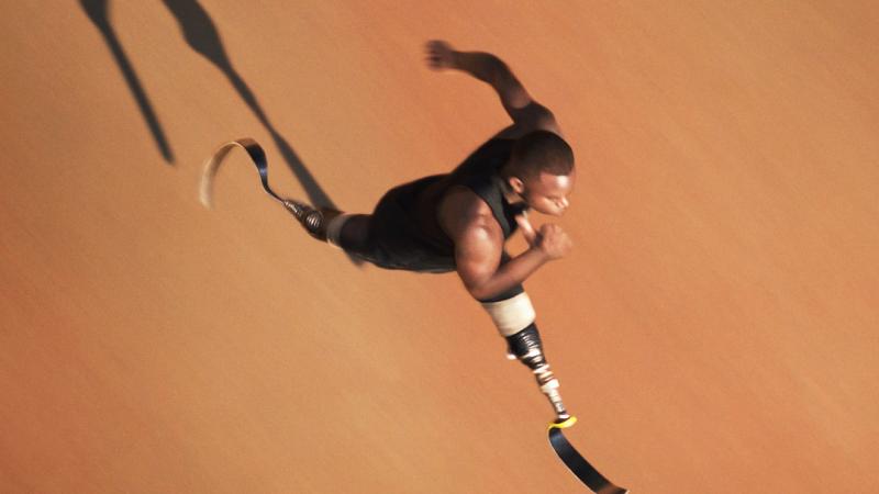 Black man with double amputee prosthesis sprinting