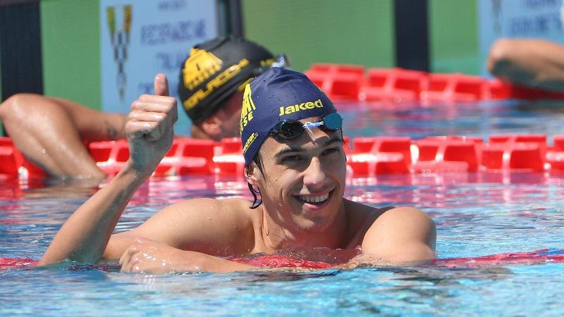 A male swimmer inside the pool giving thumbs up