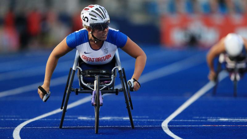 A female wheelchair racer crossing the line on a blue track