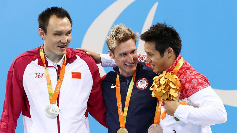 Chinese, US and Japanese vision impaired swimmers hugging on the podium