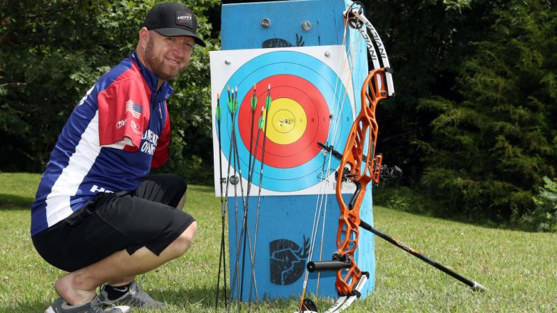 Male archer without arms poses next to his targets