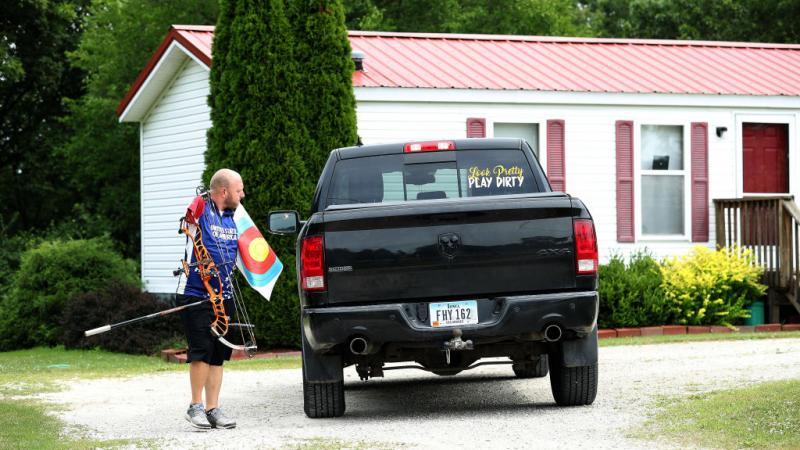 Man without arms carries archery gear to his truck