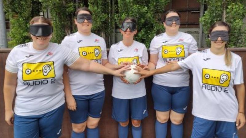 Five blind female footballer all holding a football together