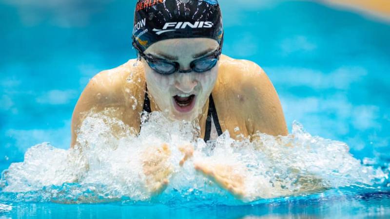 A woman with a black cap swimming breaststroke