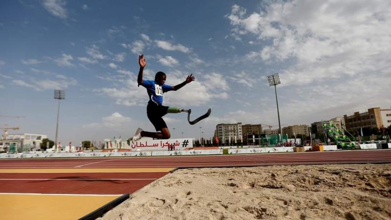 A man with a prosthetic leg jumping in an athletics track