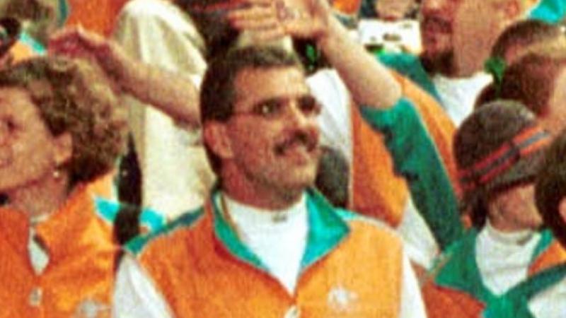 A man in orange uniform smiles in a crowd during the Opening Ceremony of the Sydney 2000 Paralympic Games.