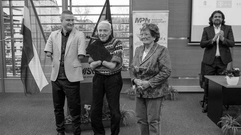 Black and white photo of elderly man without hands receiving an award 