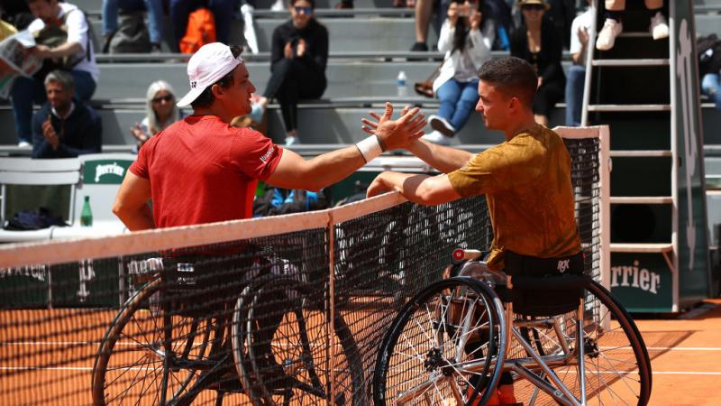 Two male wheelchair tennis players shake hands after a match
