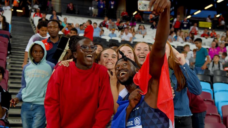 French Black man takes selfie with fans and French flag around him