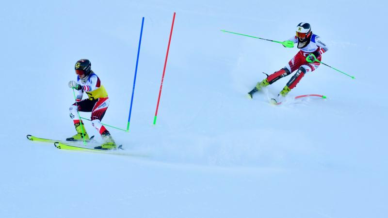 A female Para alpine skier following her guide in a competition in the snow