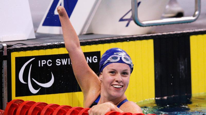 British swimmer Amy Marren lifts her arm and smiles while in the pool after a race