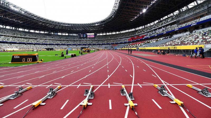 The view of a stadium with a red athletics track seen by the starting line