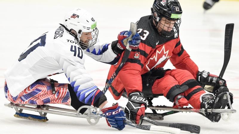Two men competing in sledges on a Para ice hockey game