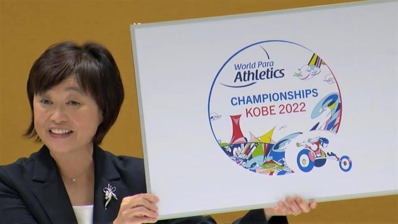 A Japanese woman holding a poster showing the logo of the Kobe 2022 World Para Athletics Championships