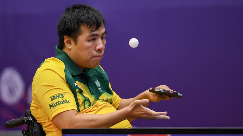 Man in wheelchair serves a table tennis ball