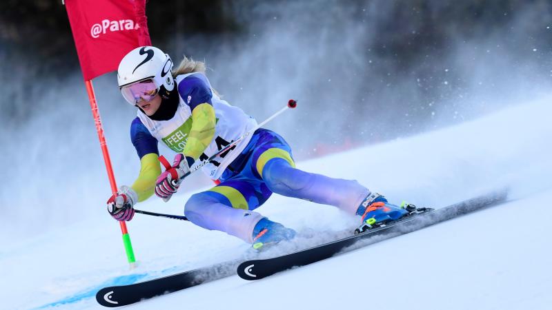 A female Para alpine skier crossing a pole in a slalom event