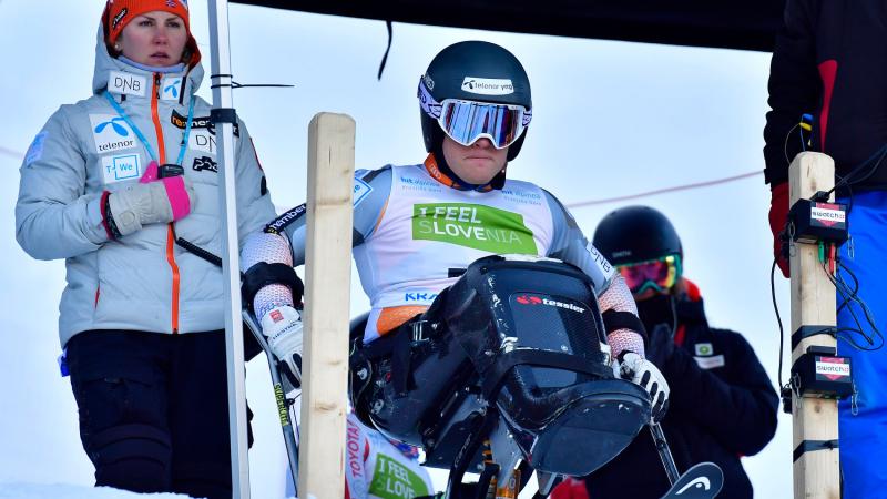 A woman observing a sit-skier at the starting gate