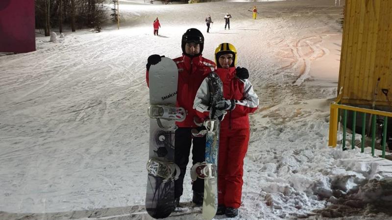 A man and a woman with snowboard gear standing in a snowy slope