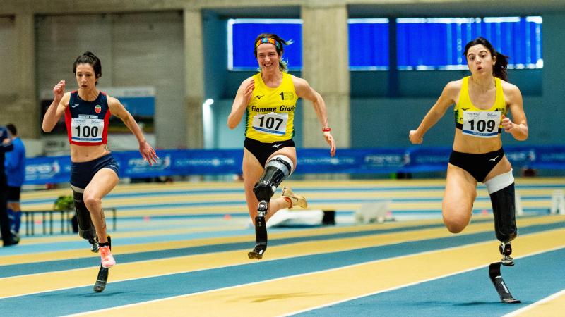 Three female blade runners in an indoor track