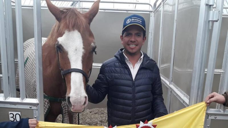 Man with his horse and a Colombian flag held in front of them