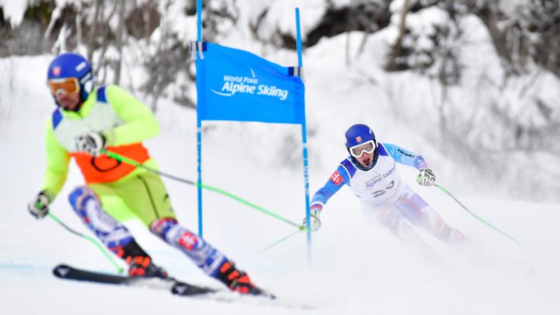 A vision impaired Para alpine skier following the guide in a downhill competition