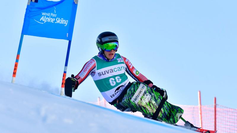 A male sit-skier competing in a Para alpine skiing giant slalom race