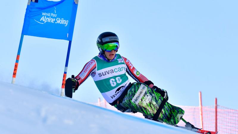 A male sit-skier competing in a Para alpine skiing giant slalom race