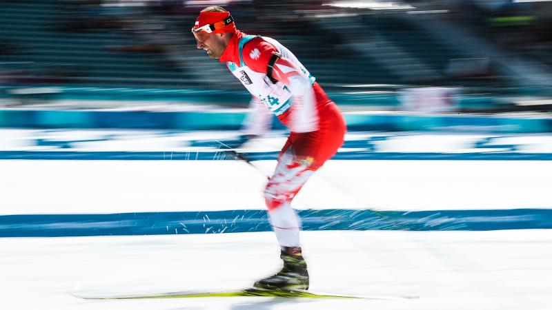 A men skiing in a cross-country competition in the snow with a blurred background 