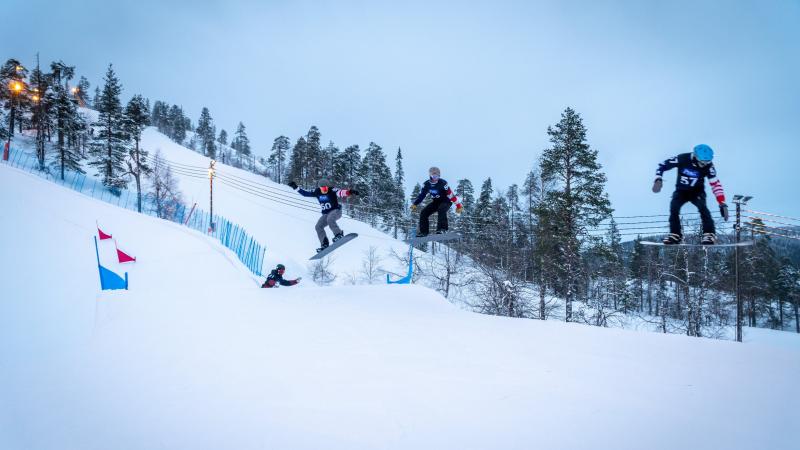 A group of male snowboarders jumping during a competition 