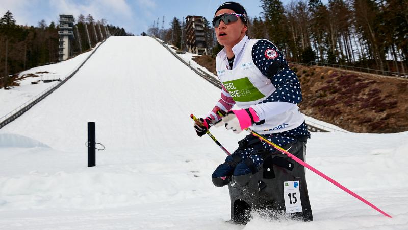 A female cross-country skier passing in front of a ski slope 