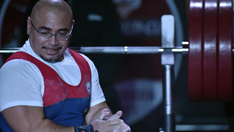 A man holding his hands on a bench press during a powerlifting competition