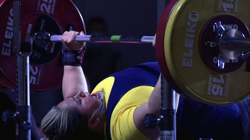 A woman lifting a bar on a bench press competition