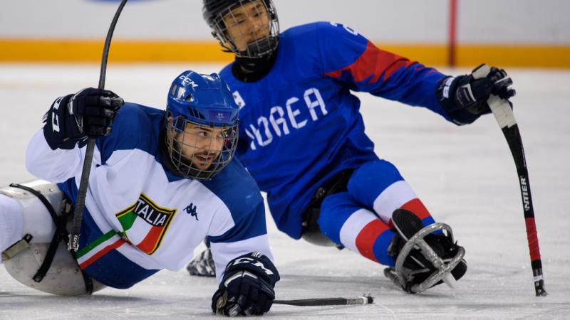 An Italian and a South Korea Para ice hockey player during a game on ice