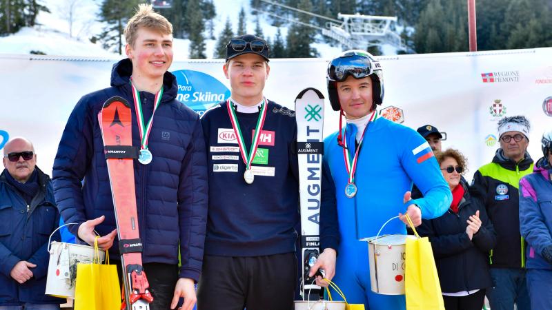 Three male standing skiers on a podium
