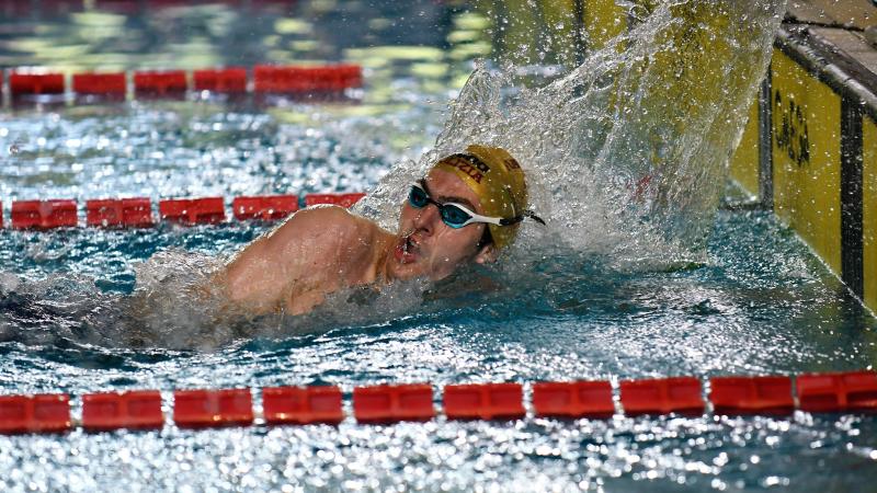 A male swimmer finishing his race in a swimming pool