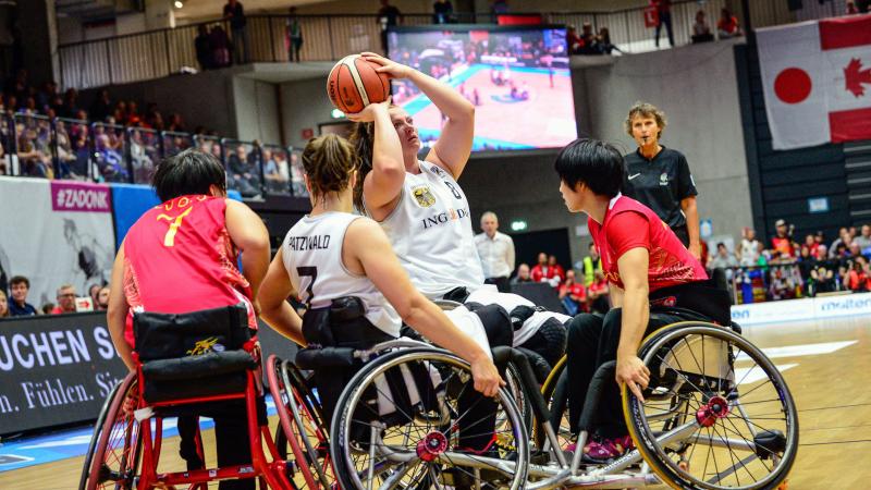 Woman shoots basketball over defenders