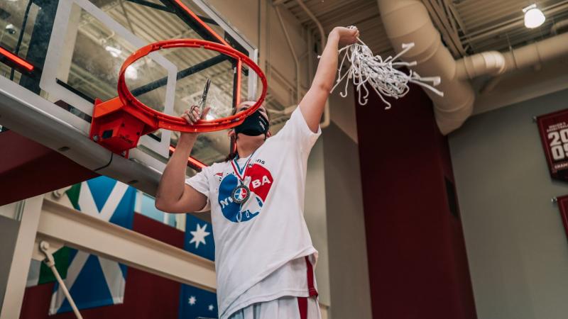 Woman cutting down a basketball net after winning a championship