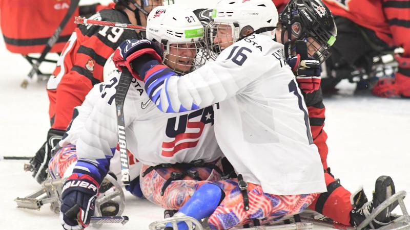 Two men in sledges celebrating with the USA uniform in a Para ice hockey game