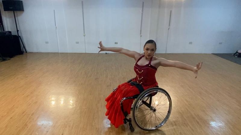 A woman in a wheelchair dancing in a room