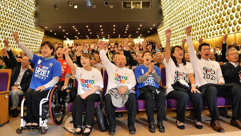 Japanese people with their fists in the air celebrating 